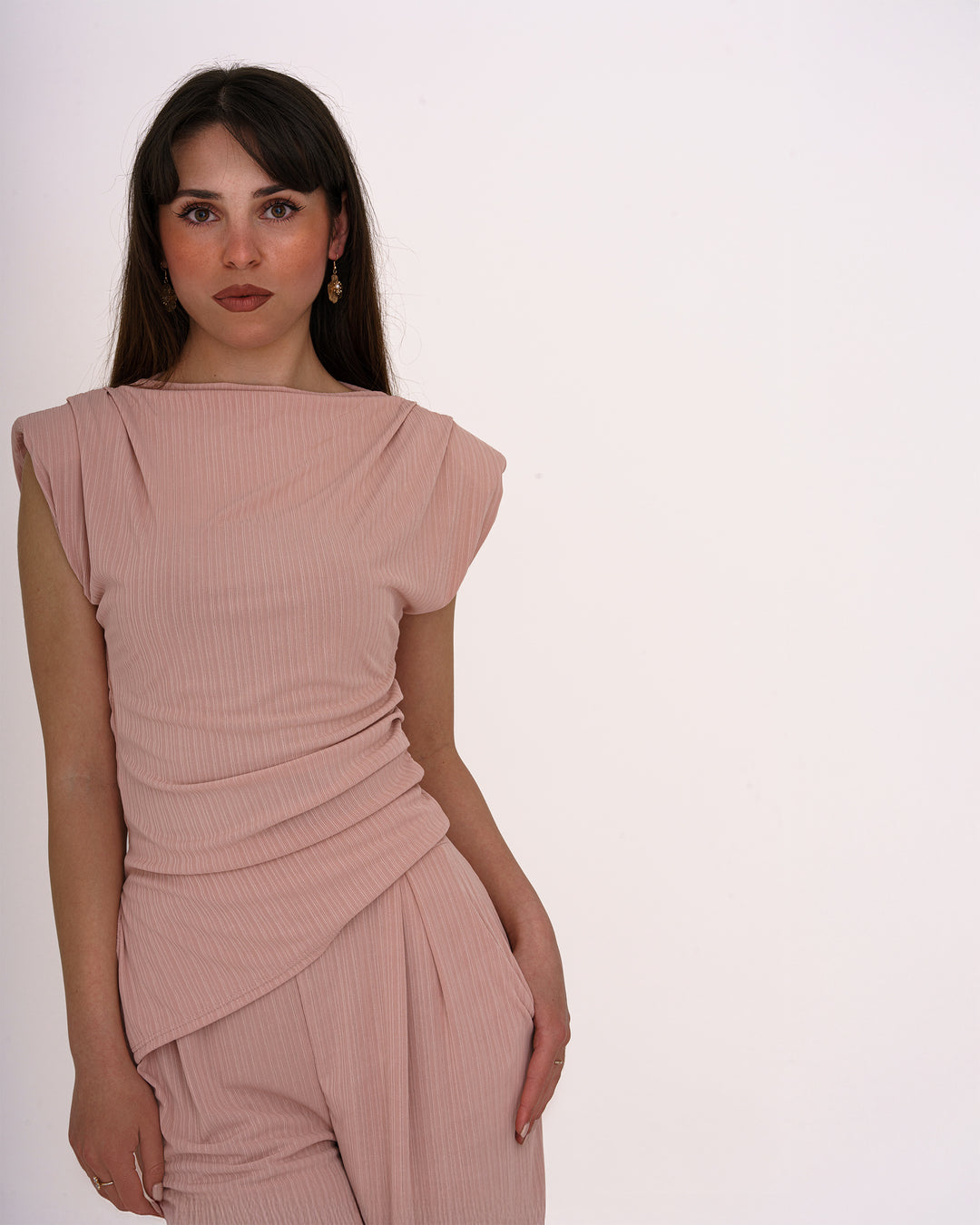 Dieser Einteiler in zartem Roséton überzeugt mit seinem femininen Schnitt und eleganten Drapierungen. Das Oberteil besticht durch raffinierte Faltenlegung und leicht überschnittene Schultern, während die weit geschnittene Hose fließend fällt und eine schmeichelhafte Silhouette zaubert. Ideal für besondere Anlässe, Business-Events oder festliche Abende. Der weich fließende Stoff sorgt für hohen Tragekomfort bei gleichzeitig stilvollem Auftritt.	•	Einteiler in elegantem Rosé
	•	Raffinierte Drapierung im Taill